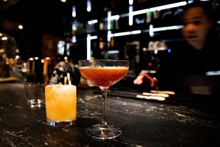 Barmaid making two cocktails.